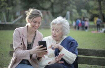 cheerful senior mother and adult daughter using smartphone together